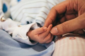 A serene moment of a parent gently holding a newborn baby, showcasing love and care in a cozy home environment.