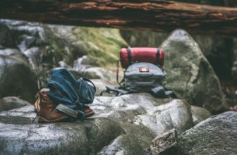 A collection of outdoor gear including a backpack, tent, and hiking boots set against a scenic nature backdrop.